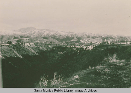 View of a canyon across Jones Bowl Road with snow on the mountains beyond