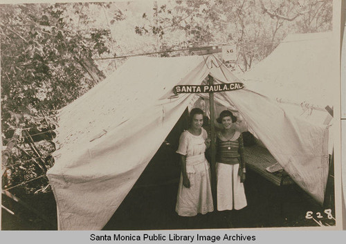 Young women stand in front of a tent "Santa Paula" at the Institute Camp, Temescal Canyon, Calif