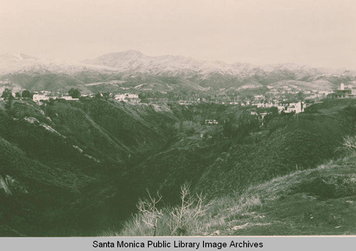 View of Temescal Canyon with snow on the mountains beyond