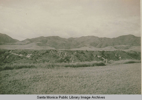 Early development in lower Temescal Canyon showing a surveyor's stake in the foreground and the Santa Monica Mountains in the background