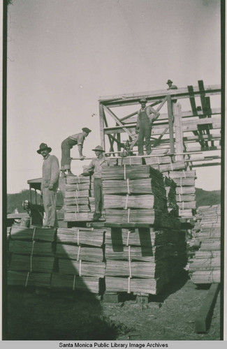 Carpenters and workmen pile lumber at Construction Center, Assembly Camp in Temescal Canyon, Pacific Palisades, Calif