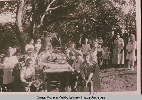 Children and a few adults at a picnic table under oak trees in Temescal Canyon, Pacific Palisades, Calif