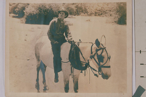 Motion picture still from Will Rogers film showing Rogers riding a horse