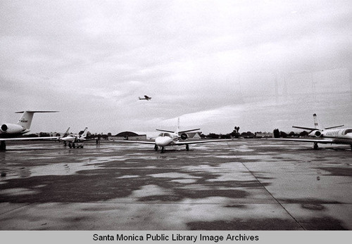 Planes on the ground, one in flight at Santa Monica Municipal Airport