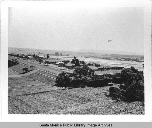 Dirigible (airship) hovers over the camouflage designed by landscape architect Edward Huntsman-Trout during World War II to cover the Douglas Aircraft Company plant in Santa Monica, Calif