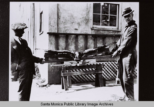 Two men hold a model of a condor with wings outstretched at the Douglas Aircraft Company's Wilshire plant (26th Street and Wilshire Blvd.)