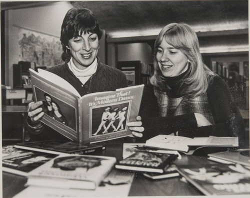 Two library staff looking at a book