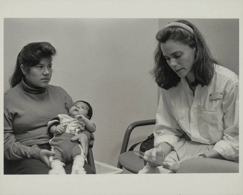 Mother holding her baby and listening to a staff at the Venice Family Clinic, Venice, Calif