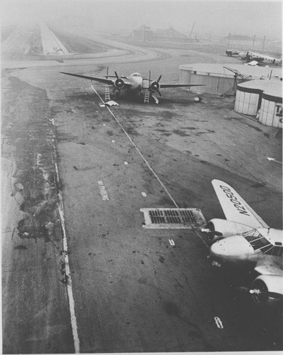 Two airplanes (N20500) near a drain on the tarmac at Santa Monica Municipal Airport, January 19, 1953