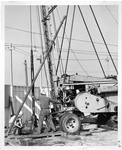 Two workers and a Bucyrus Erie machine at the construction site of Pacific Ocean Park, Santa Monica, Calif