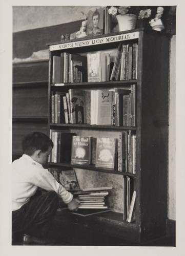 Boy browsing books on the Mercer Watson Lucas Memorial shelf in the Boys and Girls Room