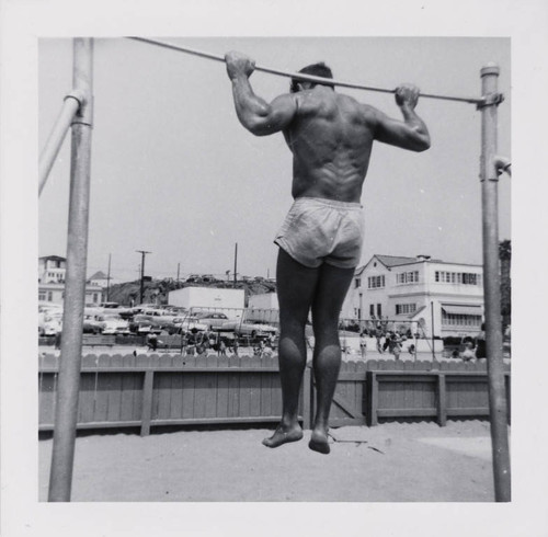 Man working out using pullup bars on Muscle Beach, Santa Monica, Calif