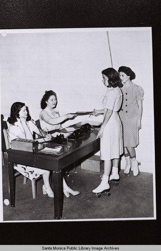 Two women on roller skates deliver documents to two other women in (Section) A2 of the Douglas Aircraft Company Santa Monica plant on May 12, 1943