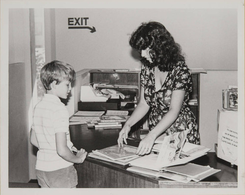 Library staff helping a boy check out his books