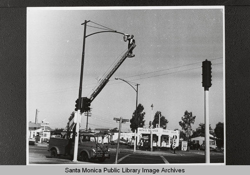 Changing the mercury vapor lamp at Fourteenth Street and Pico Blvd. across from Roth's Service & Douglas Gasoline ,Santa Monica, Calif