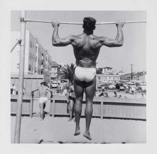 Man working out using pullup bars on Muscle Beach, Santa Monica, Calif