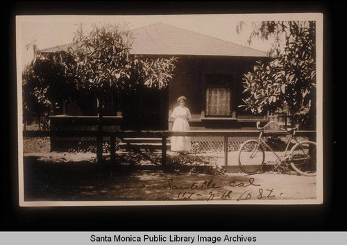 Woman in her front yard with a bicycle, Sawtelle, Calif