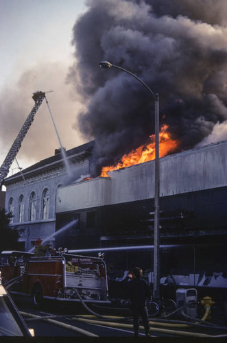 Flames and smoke shooting from the roof of Thrifty Drug Store at 326 Wilshire Blvd