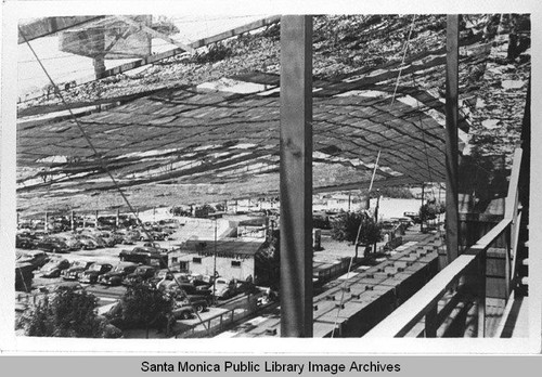 View of automobiles parked underneath the camouflage designed by landscape architect Edward Huntsman-Trout to conceal the manufacture of military aircraft at the Douglas Aircraft Company Santa Monica plant during World War II