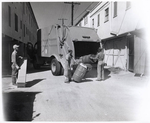 Sanitation worker disposing trash into a sanitation truck in Santa Monica, Calif