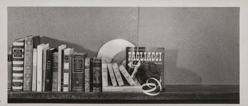 Books and a reel of recording of Pagliacci on top of a bookshelf