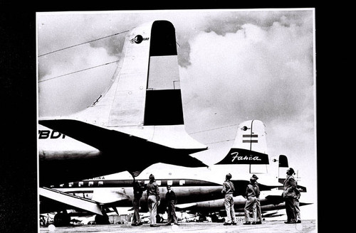 Boy Scouts examining the tails of two airplanes on the tarmac while visiting Douglas Aircraft Company in Santa Monica