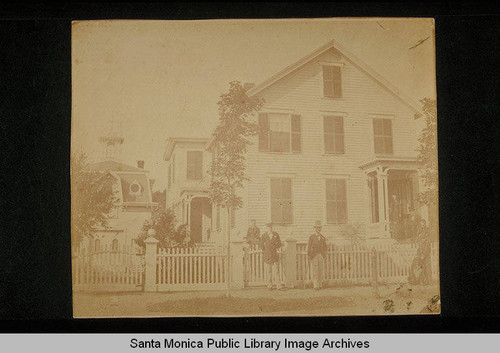 Unidentified two-story house with picket fence in Santa Monica, Calif. : Gentlemen and ladies in formal dress are on the steps and in the yard