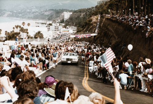 Crowds cheering as O.J. Simpson runs the Olympic torch up the California Incline on July 21, 1984, Santa Monica, Calif