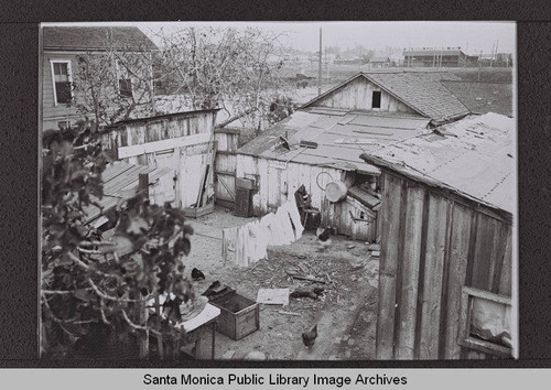 View of the Olson Lumber Company, Fourth Street and Southern Pacific Park, across from a backyard clothesline and shacks, Santa Monica, Calif