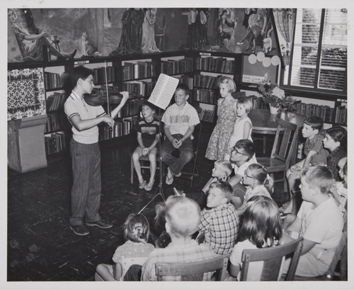 Boy playing the violin in front of a group of children