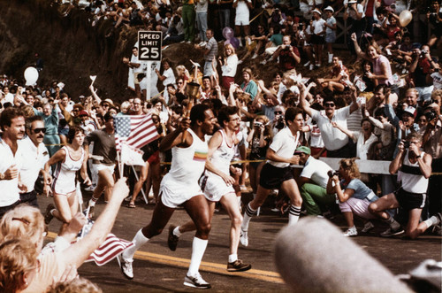 Crowds cheering as O.J. Simpson runs the torch up the California Incline on July 21, 1984, Santa Monica, Calif
