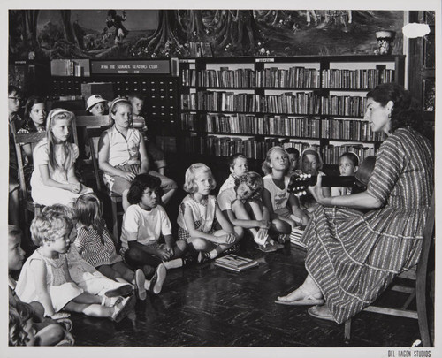 Woman playing the guitar in front of young patrons in the Boys and Girls Room