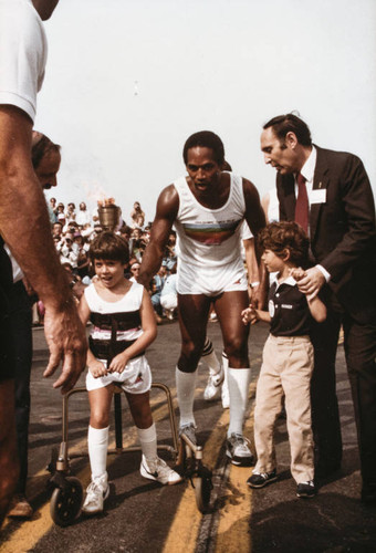 Seven-year-old Michael Bailey starting his Olympic torch relay as O.J. Simpson and Ken Edwards look on, July 21, 1984, Santa Monica, Calif