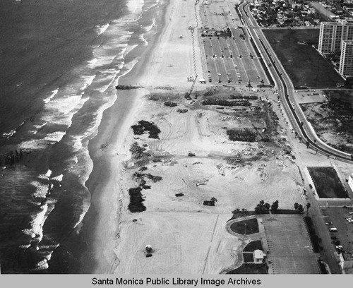 Remains of the Pacific Ocean Park Pier looking north to the Santa Monica Shores Apartments and beach parking lots, April 9, 1975, 11:00 AM