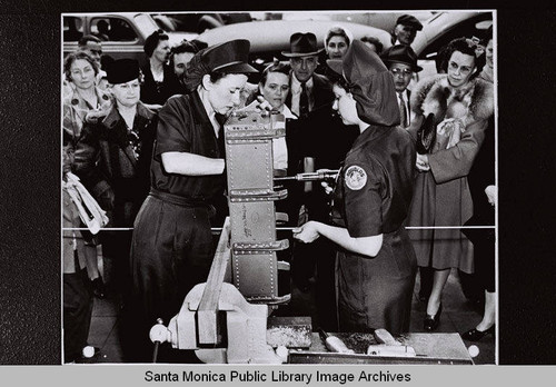 Two Douglas employees demonstrate using tools to a group of women at the Douglas Aircraft Company plant "Opportunity Day" during World War II