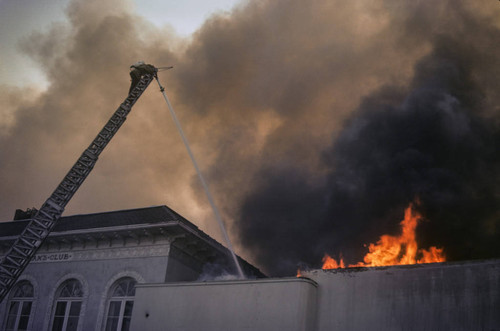 Firefighter on top of a ladder battling a blaze at Thrifty Drug Store at 326 Wilshire Blvd