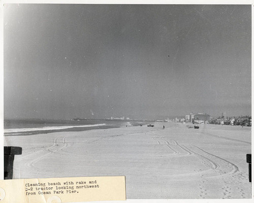 Beach cleaning with rake and a D-2 tractor looking northwest from Ocean Park Pier, Santa Monica, Calif