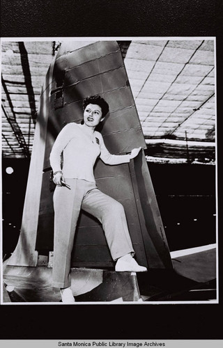 Douglas Aircraft Company public relations shot of a woman standing on the tail section of an airplane holding a screwdriver during World War II