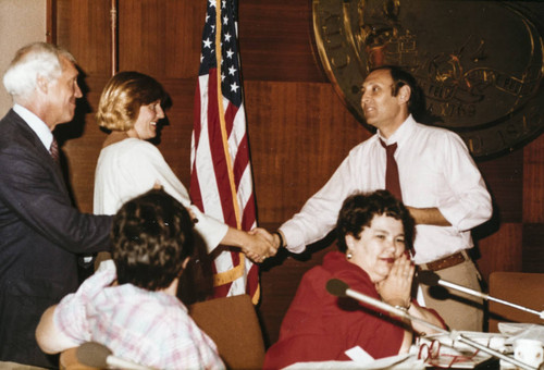 Santa Monica Mayor Ken Edwards (in red necktie) and others at the presentation of the Games of the XXIII Olympiad flag in the Santa Monica City Council Chambers, July 21, 1984