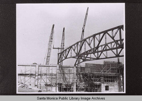 Construction of the Santa Monica Civic Auditorium showing a crane with roof beam, July, 1957