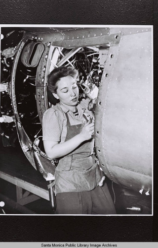 Douglas Aircraft Company employee with gauge and wrench working on aircraft during production drive, World War II