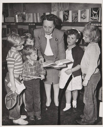 Librarian showing a book to young patrons in Boys and Girls Room