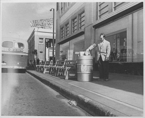 A.F. Smith, City Field Investigator deposits trash in a bin down the block from Security First National Bank, Santa Monica, Calif