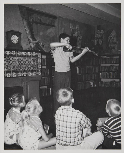 Boy playing the violin in front of a young audience