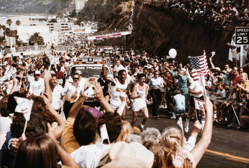 Crowds cheering as O.J. Simpson runs the Olympic torch up the California Incline on July 21, 1984, Santa Monica, Calif