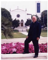 Thomas P. O'Malley, S.J., standing on the edge of Alumni Mall