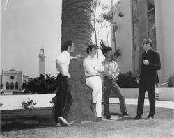 Richard Robin, S.J., speaking with students under a tree