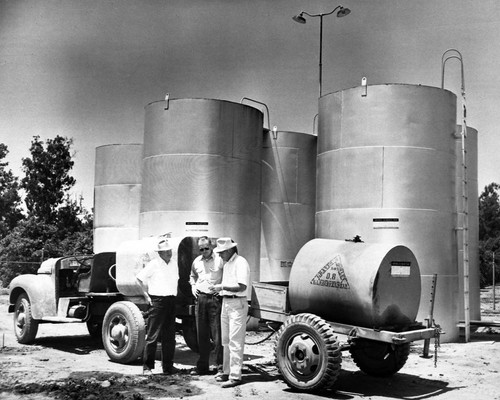 Storage tanks at Graves & Howley Pest Control with Bill Graves, Paul Andres, and a salesman, Tustin, ca. 1960