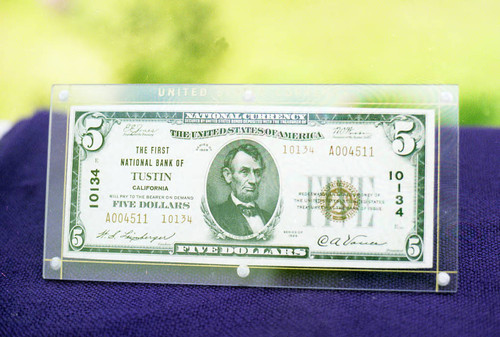 Five dollar bill from the First National Bank of Tustin, series of 1929, signed by Vance and Leinberger and encased in plastic, ca. 1929