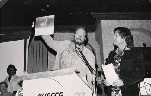 Corky Carroll awards Allan "Splash" Seymour with Surfer magazine's "Worst Surfer" award